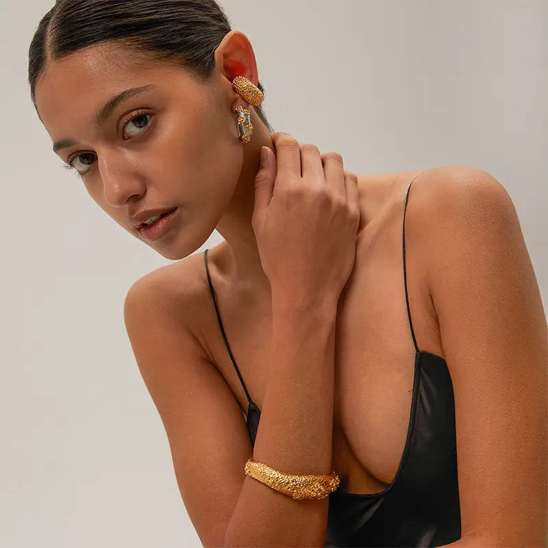 Model wearing Fleur de Lune Flower gold cuff and matching earrings with floral motifs