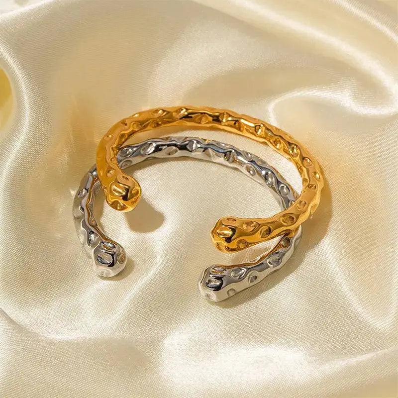Hammered gold and silver bracelets with raised patterns on soft silky fabric.