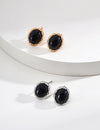 Elegant black agate earrings set in gold, featuring a woven design, displayed on a white background.