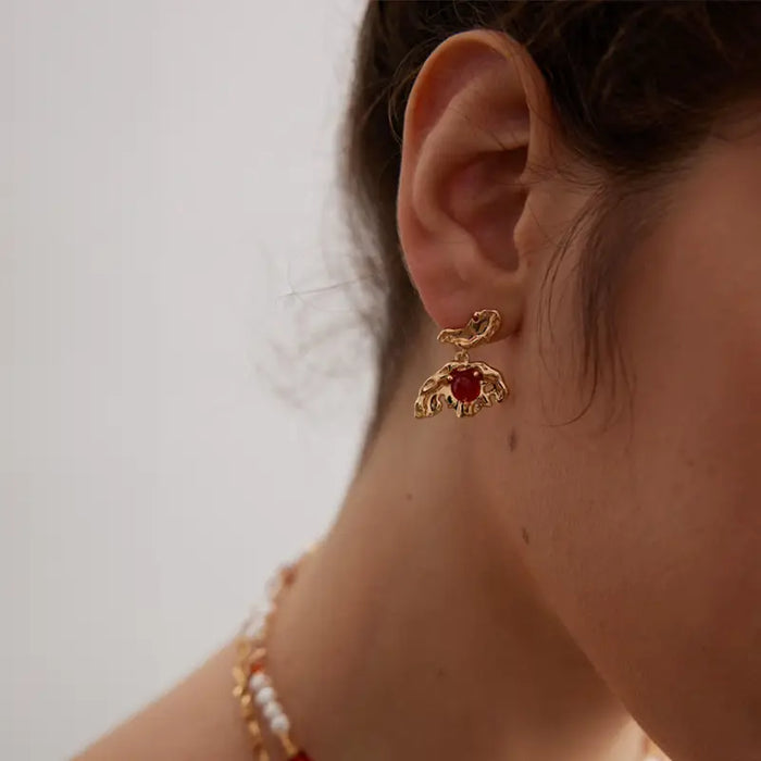 Model wearing Aimee Gold Agate Drop Earrings, showcasing the intricate gold detailing and vibrant red agate stones, styled with layered gold and pearl necklaces.