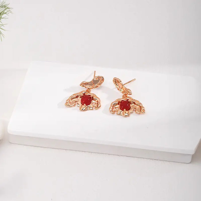 A close-up back view of Aimee Gold Agate Drop Earrings, showcasing the textured gold metalwork and secure fastening with the vivid red agate centerpiece.