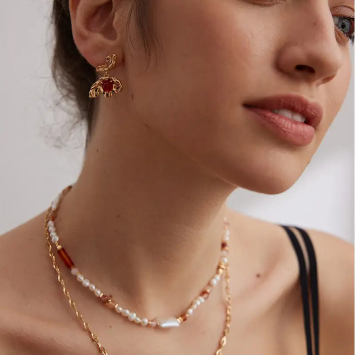 Side profile of a model wearing Aimee Gold Agate Drop Earrings, emphasizing the bold red agate stones and organic gold shape that create a striking, luxurious look.