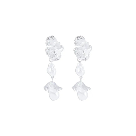 he image displays a pair of Aimee Leaf Silver Pendant Earrings, featuring a serene all-silver design. Each earring starts with a delicate leaf motif at the top, detailed with intricate vein patterns that highlight the leaf's naturalistic design. Suspended from the leaf are two irregularly shaped baroque pearls, creating a graceful cascade. The earrings shimmer with a pure, silvery sheen, offering a sophisticated and elegant accessory option.