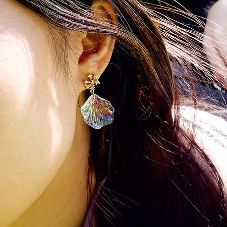 Close-up of Aimee Shell Earrings showcasing iridescent shell design and delicate floral stud, worn by a model, capturing the earrings' vibrant colors and intricate details.