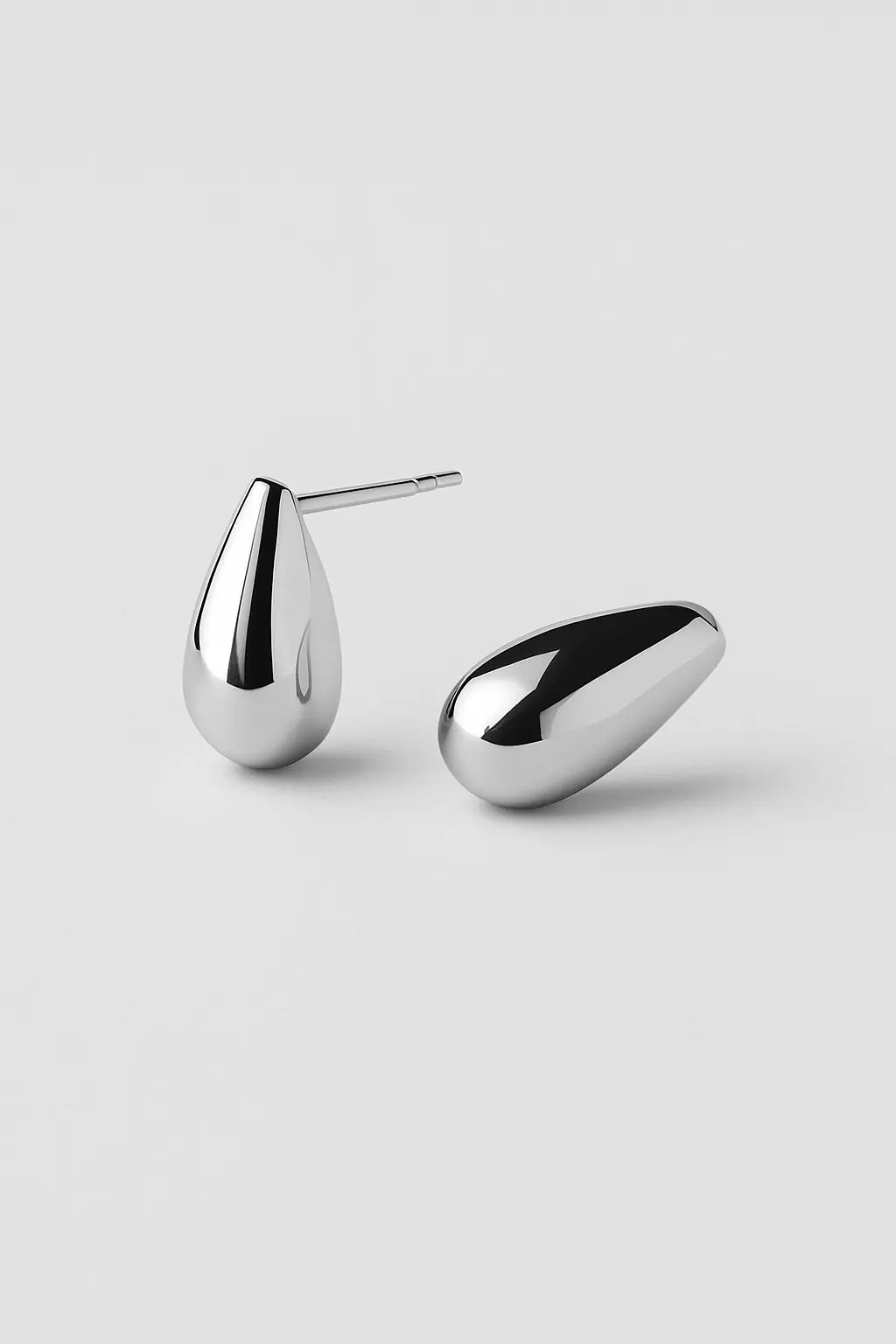 Pair of silver teardrop-shaped earrings on a light gray background_Anais&Aimee