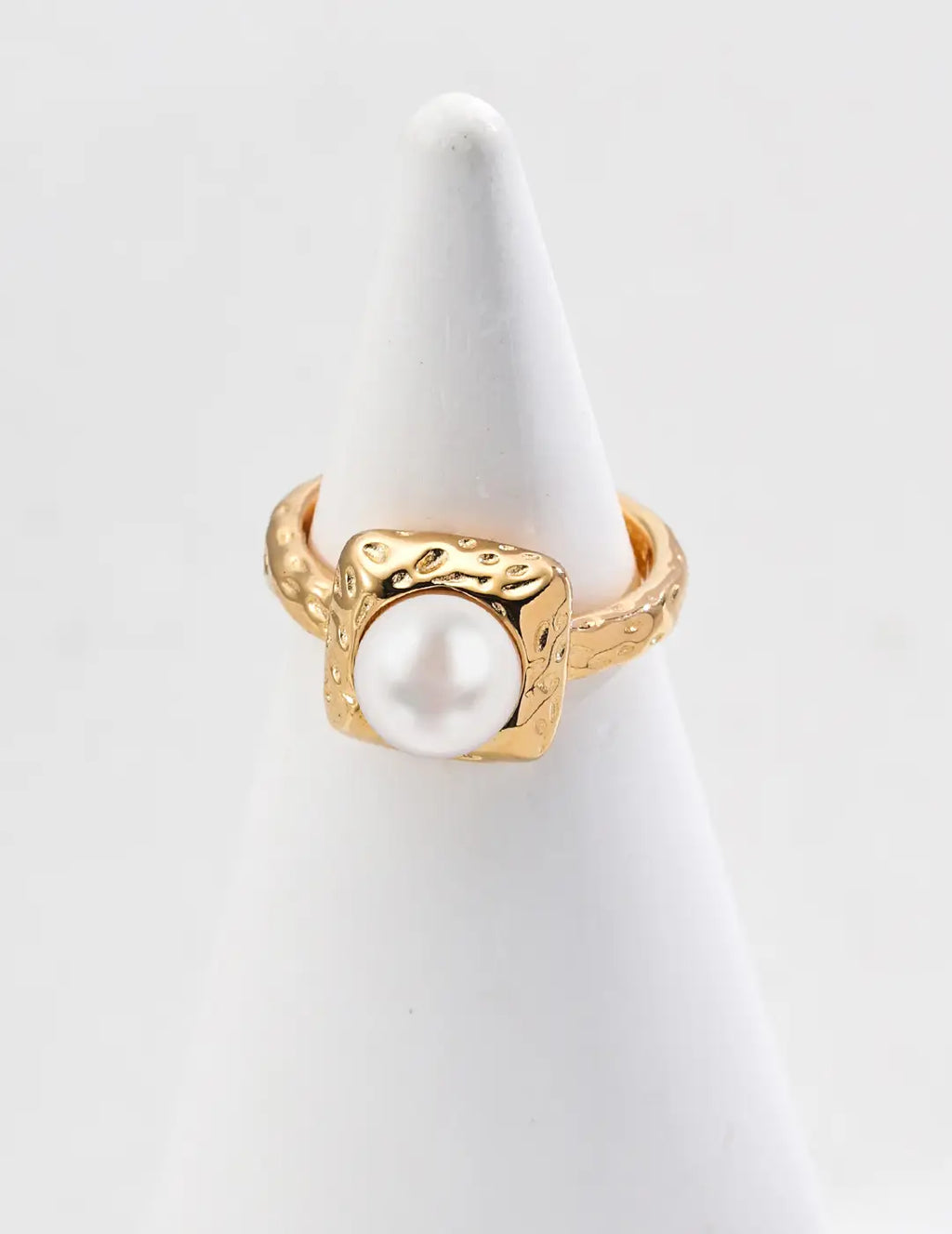 Gold ring with a pearl on a white stand