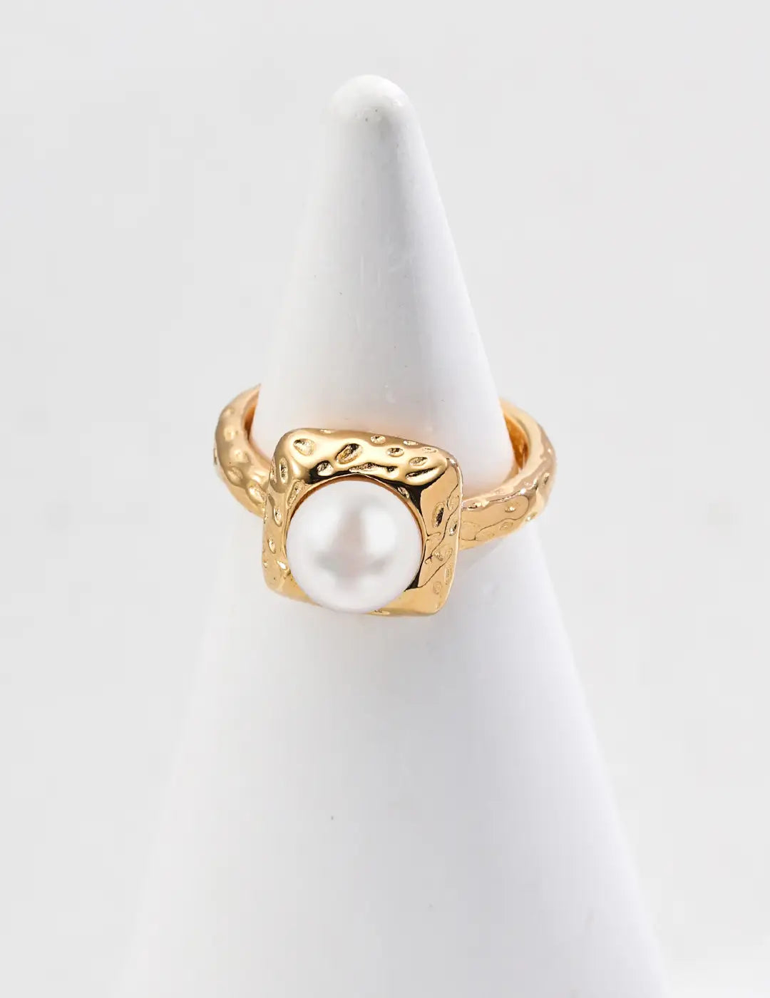 Gold ring with a pearl on a white stand