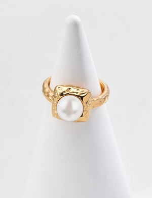 Gold ring with a pearl on a white stand