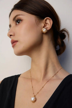 Woman wearing pearl earrings and necklace against a plain background
