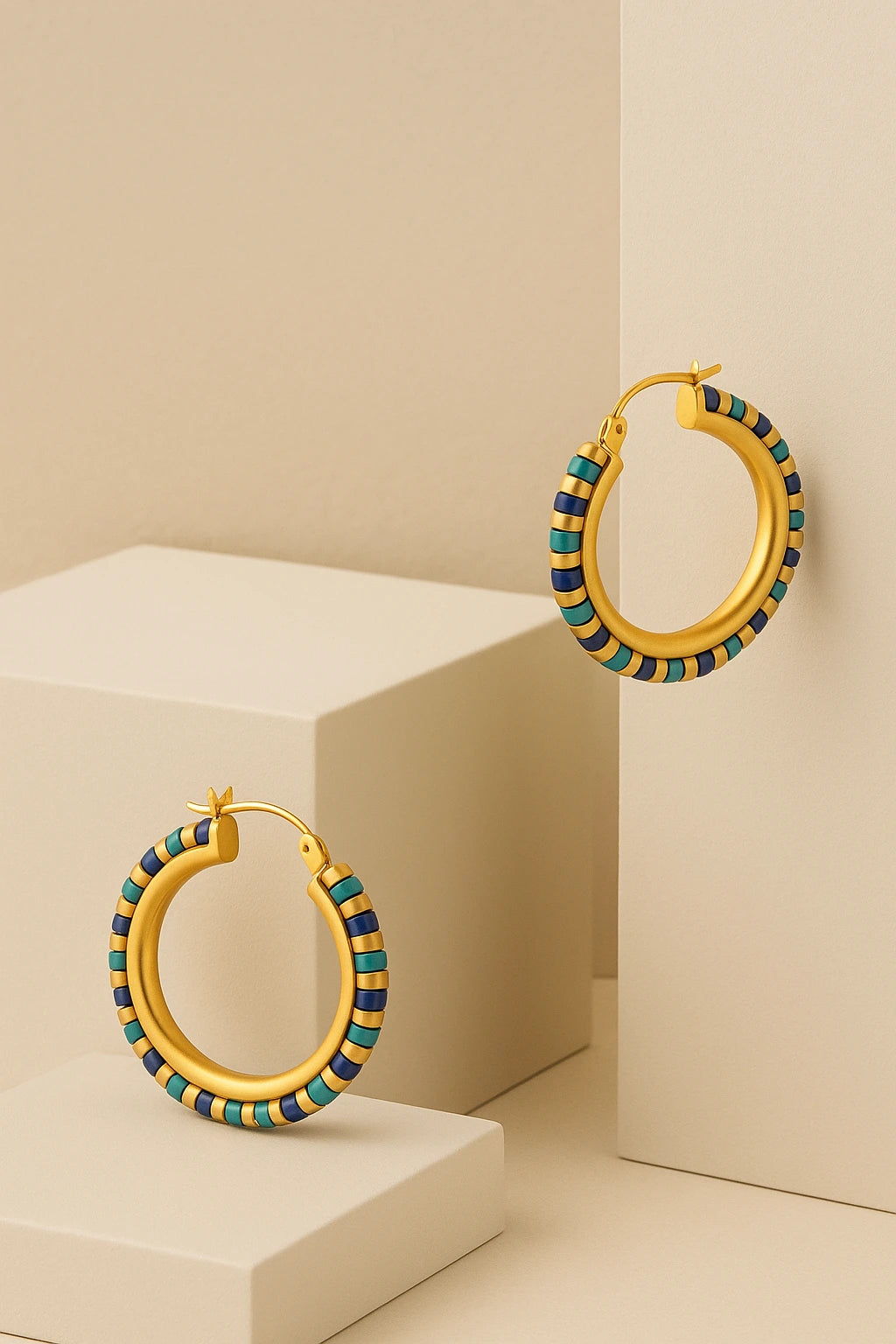 Beaded turquoise gemstone hoop earrings elegantly styled against geometric cream-toned blocks.

