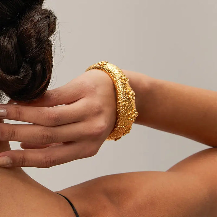 Model wearing the Blooming Flower Textured Cuff on her wrist, highlighting the intricate gold floral motifs and textured finish