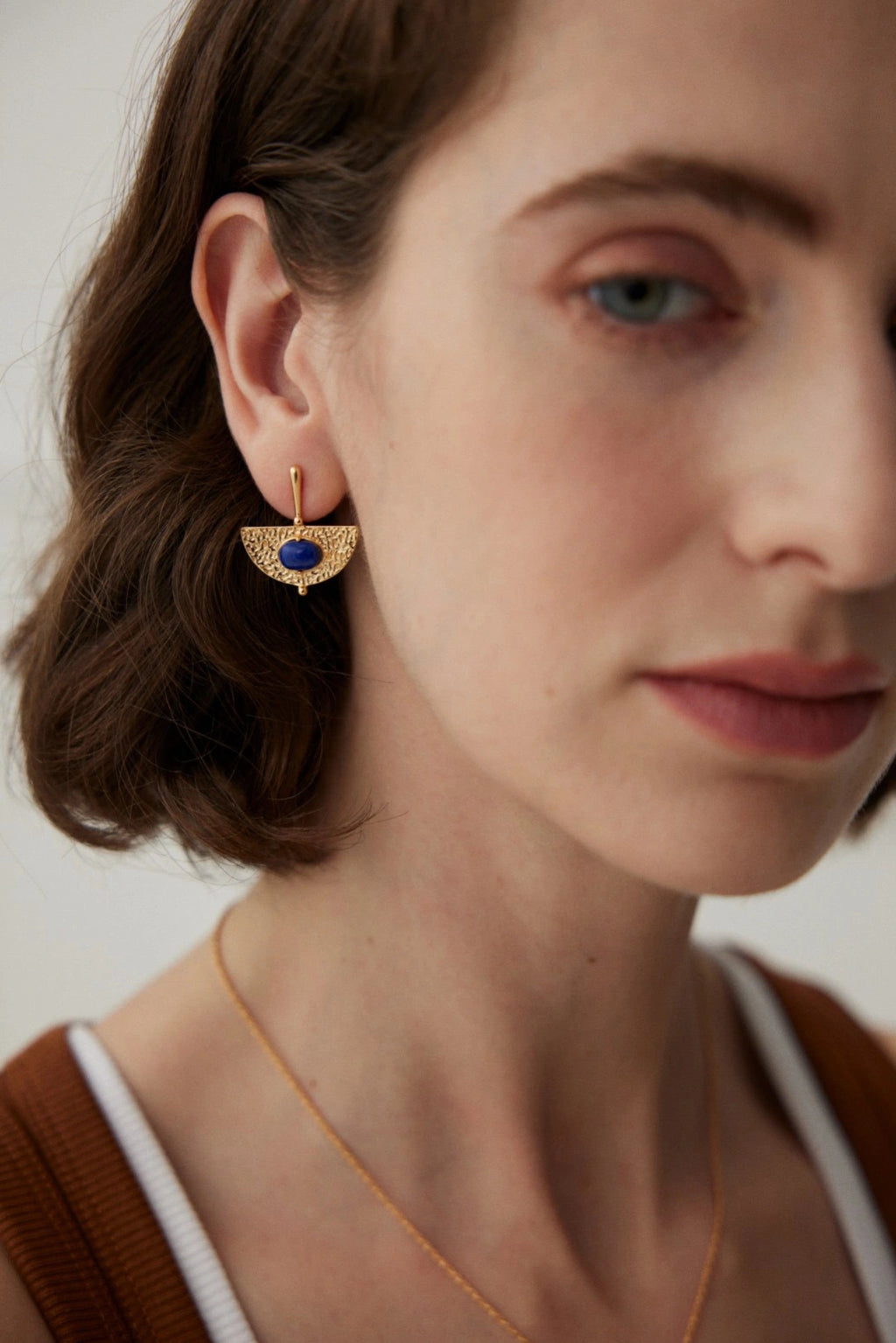 Close-up of woman wearing handmade lapis gemstone earrings – textured gold statement earrings UK by Anais & Aimee