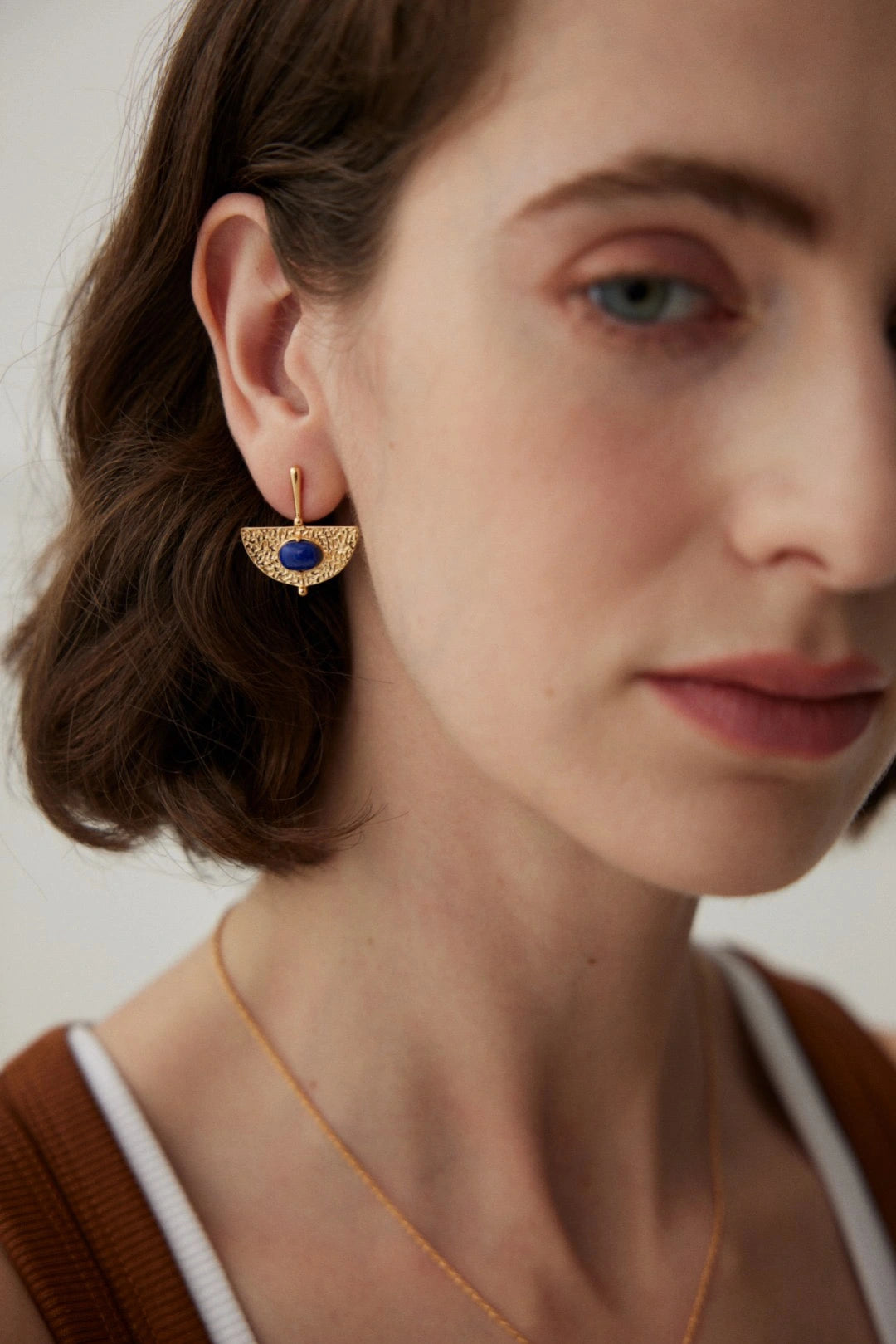 Close-up of woman wearing handmade lapis gemstone earrings – textured gold statement earrings UK by Anais & Aimee