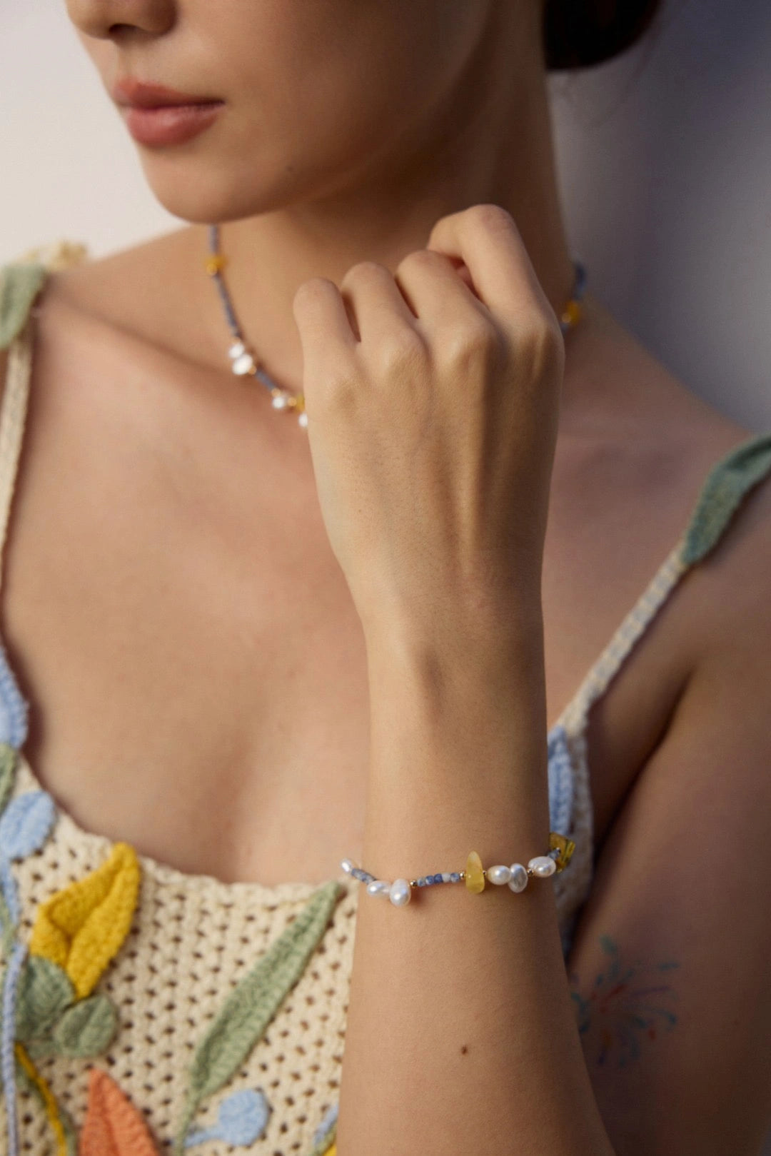 Profile of model wearing Celeste Harmony bracelet and necklace with soft makeup and crochet top.