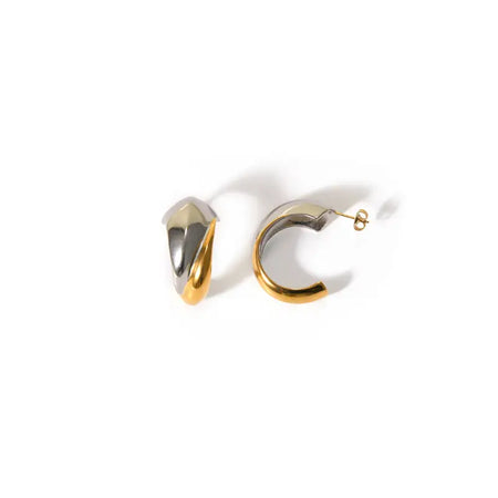 a pair of elegant half-hoop earrings, each featuring a dual-tone design with gold and silver finishes. The design is modern and minimalist, with a smooth, polished surface that reflects light beautifully. The earrings' unique structure combines the warmth of gold with the coolness of silver, making them versatile enough to complement various outfits and occasions. 
