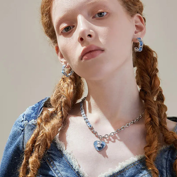 Close-up of the Denim Heart Sterling Silver Necklace on a model, featuring a silver chain interwoven with denim and a heart-shaped pendant with a bear detail