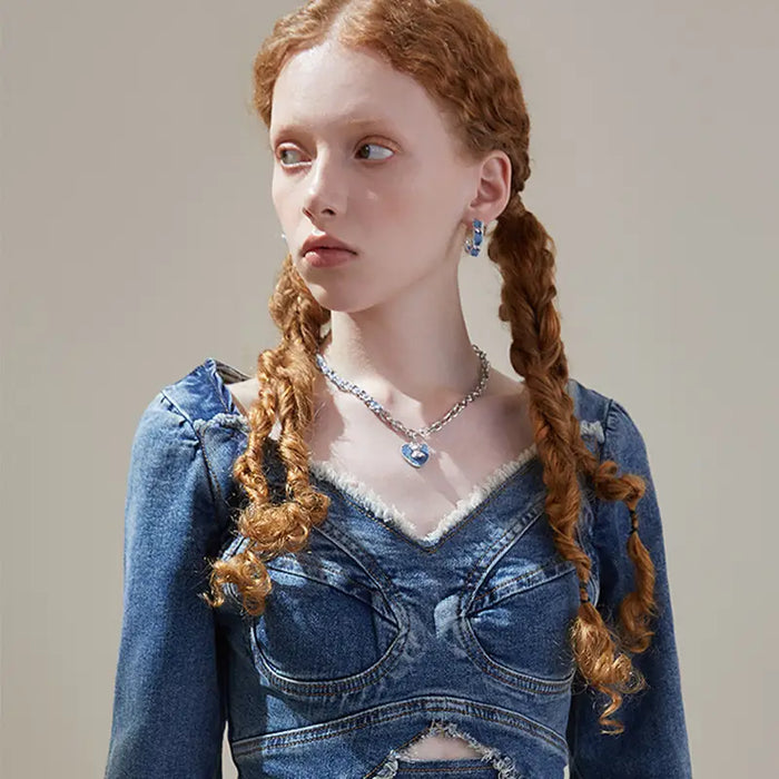 Side profile of a model showcasing the Denim Heart Sterling Silver Necklace and matching denim hoop earrings, styled with a frayed denim outfit for a bold statement