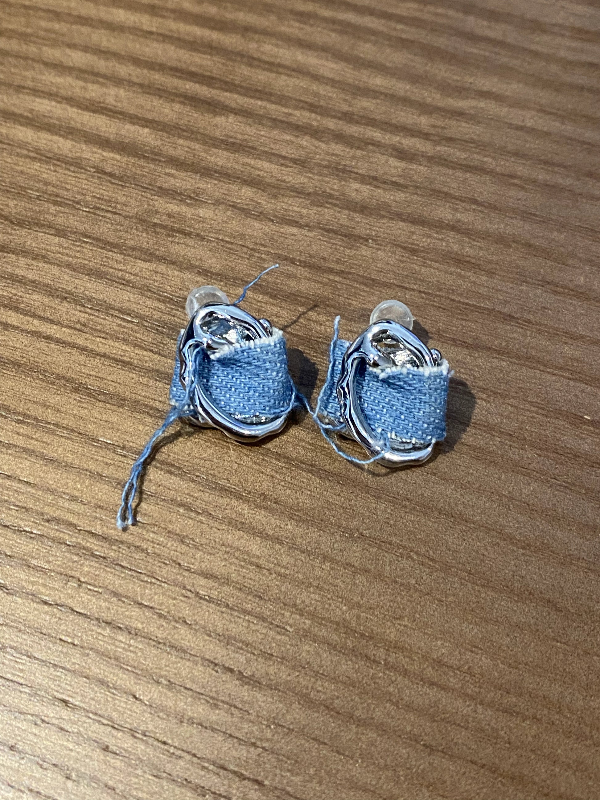 Anais&Aimee Denim Angel Silver Statement Earrings on brown background