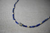 Detailed view of the Camile Turquoise Lapis Lazuli Pendant Necklace, showcasing the lapis lazuli beads and a round stone centerpiece on a neutral fabric background