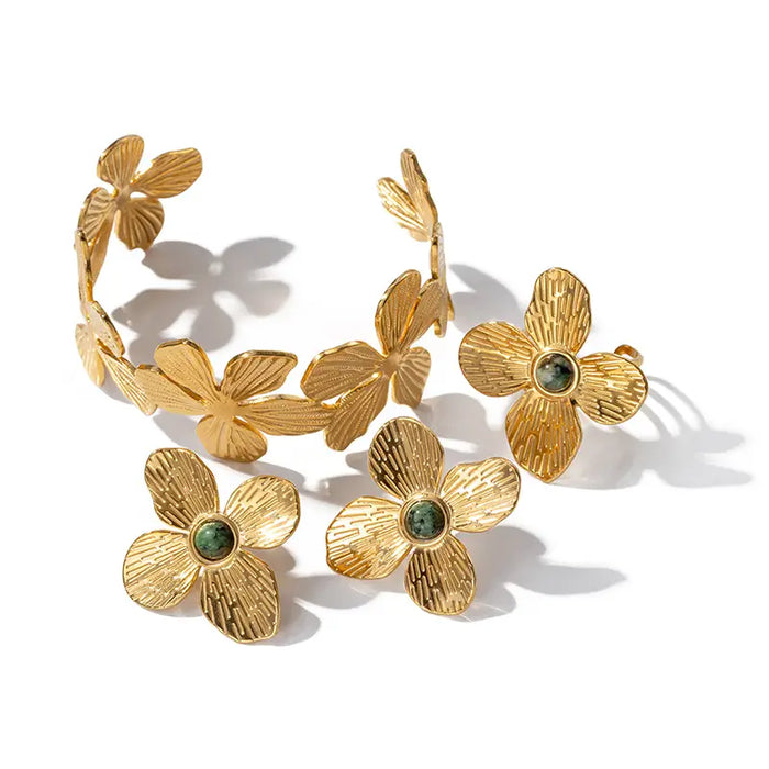 Anais & Aimee Dogwood Flower Jewelry Collection - featuring a luxurious gold-plated cuff bracelet and matching stud earrings adorned with detailed dogwood flower motifs and green gemstones. This elegant collection is perfect for adding a touch of nature-inspired sophistication to your look.