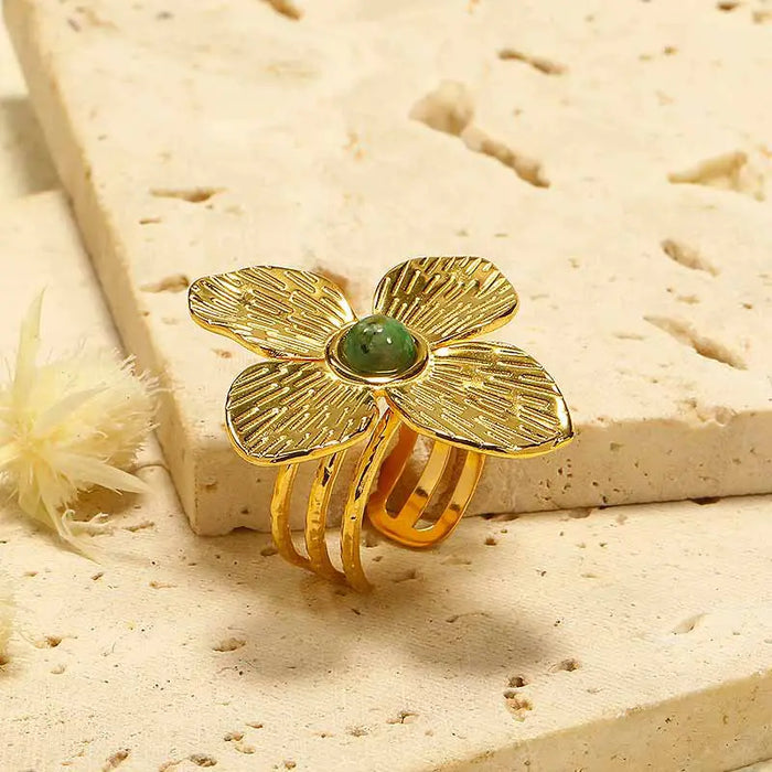 Close-up of the Anais & Aimee Dogwood Flower Cuff Ring, featuring an 18K gold-plated base and a genuine green gemstone. The intricate petal design symbolizes rebirth and strength, making it a sophisticated and timeless accessory.