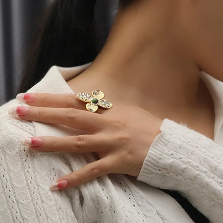 Model wearing the Anais & Aimee Dogwood Flower Cuff Ring, featuring an 18K gold-plated base and a genuine green gemstone. The ring symbolizes rebirth and strength with intricate petal detailing, adding an elegant and timeless touch to any outfit.