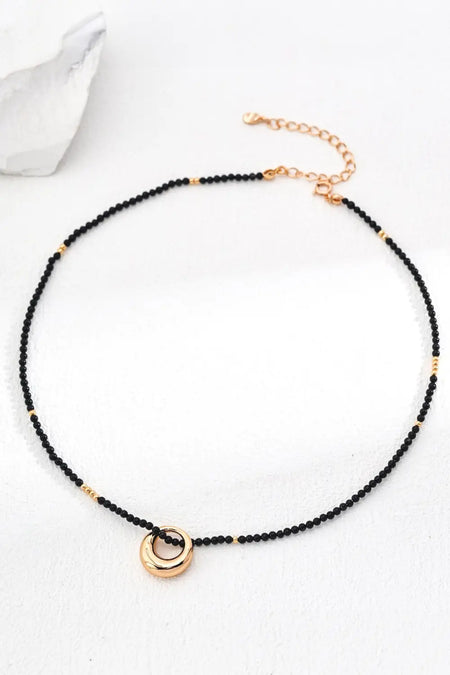  A Donut Sterling Silver Agate Necklace displayed on a clean white background, showcasing its minimalist black and gold bead design with a statement donut pendant.