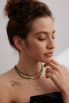 Side profile of a model wearing the Emerald Green Necklace Choker by Anaïs & Aimee, layered with complementary necklaces to showcase its vibrant green and gold tones.