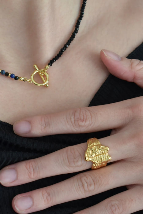 Anaïs & Aimee’s Erosia Organic Gold Statement Ring and black bead toggle necklace on a model, highlighting the textured gold finish