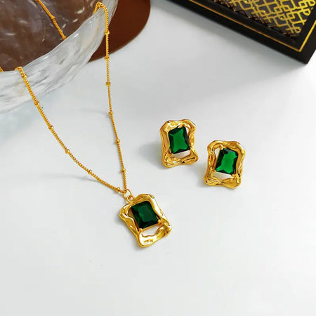 Evergreen Emerald Stud Earrings set featuring a matching necklace, all crafted in polished gold-tone metal with vibrant green emerald-cut gemstones. This high trending accessory set adds a touch of timeless elegance and sophistication, perfect for making a stylish statement.