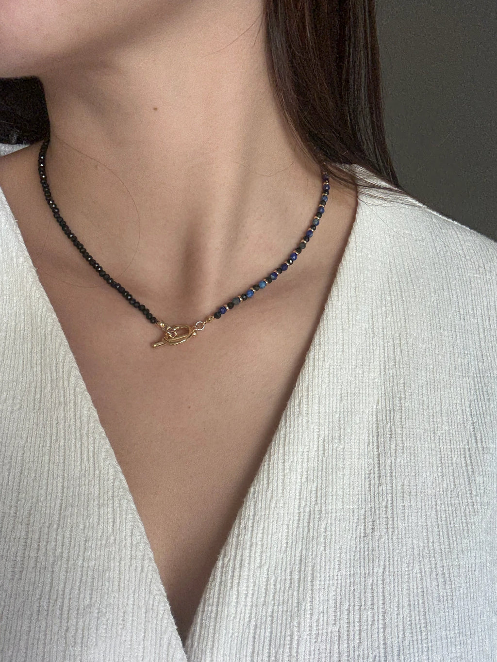 Model wearing the Gempires Necklace, styled simply over a white textured blouse to highlight the necklace’s elegance and neckline fit.

