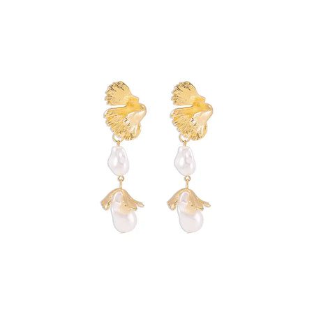 Each earring features a textured, gold ginkgo leaf design at the top, mimicking the natural veining and shape of a leaf. Hanging from the leaf are two elements: a uniquely shaped baroque pearl and a small golden pendant shaped like a teardrop. 