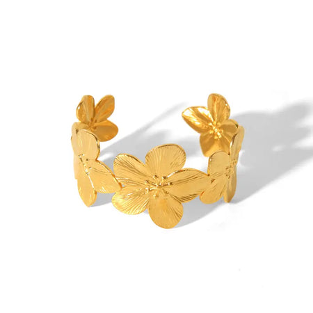 Gold cuff bracelet adorned with large, detailed floral motifs, showcasing an open design and a polished finish.
