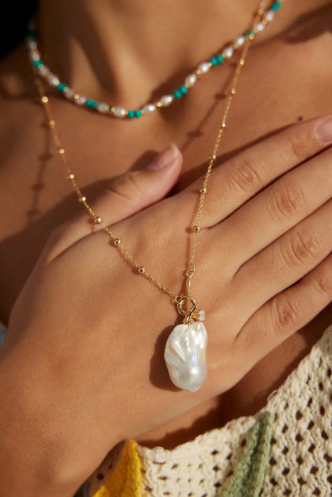 Close-up of the Luxury Baroque Pearl Necklace by Anaïs & Aimee, elegantly worn by a model, showcasing the unique pearl pendant and delicate gold chain design