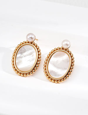 Pair of gold-framed earrings with pearl accents on a white background