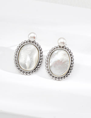 Pair of silver earrings with pearl-like stones on a white background