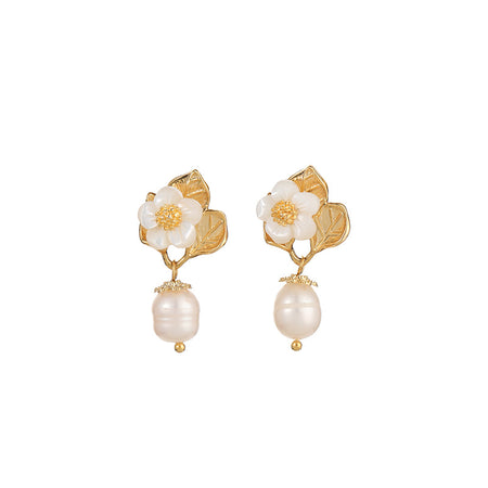 The image displays a pair of elegant Petal Flora Drop Earrings. Each earring features a beautifully crafted gold floral design, topped with a delicate white petal and a central cluster of tiny golden beads resembling pollen. Below the floral element, a large, smooth baroque pearl hangs gracefully, capped with a small gold accent. The earrings combine classic elements with a touch of modern flair, ideal for enhancing any ensemble.