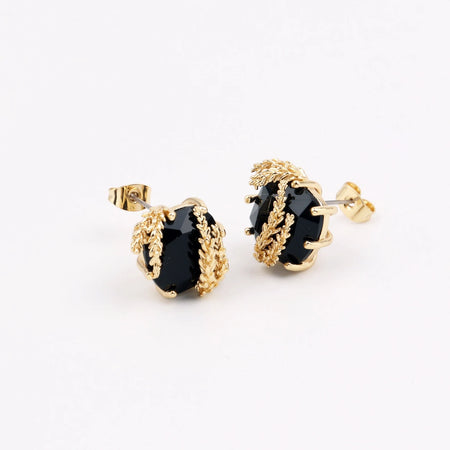 Patchouli Flower Black Gem Stud Earrings by Anaïs & Aimée, featuring faceted black gemstones encased in detailed gold floral accents, set against a white background.