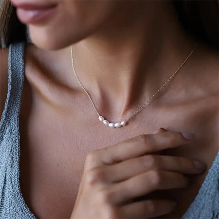 Woman wearing a Rose Gold Freshwater Pearl Necklace with delicate pearls elegantly strung on a fine rose gold chain, showcasing its graceful fit around the neckline. Elegant and timeless jewelry piece.