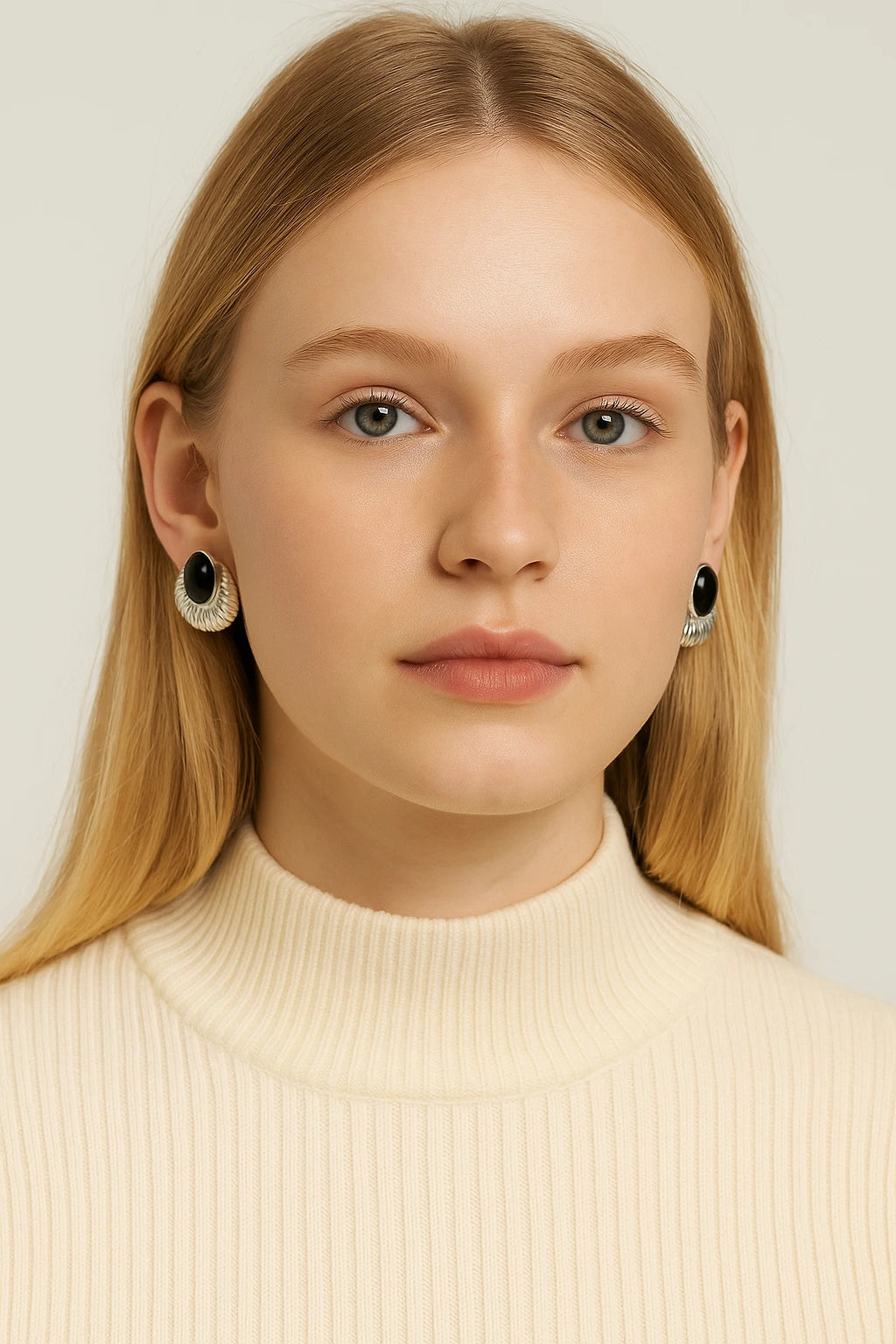 Young blonde woman in cream turtleneck wearing vintage silver obsidian earrings.