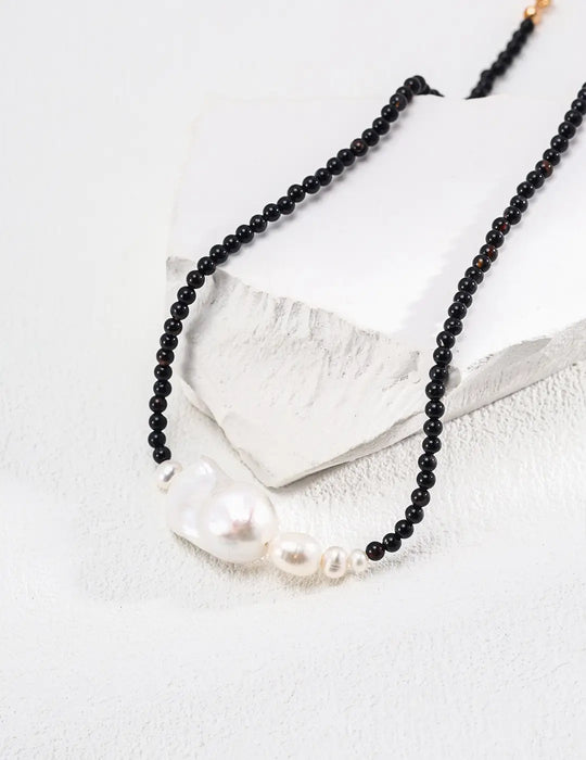 Serenity Black Obsidian Pearl Necklace displayed elegantly on a white platform, highlighting the contrast between black obsidian and white pearls - Anais & Aimee