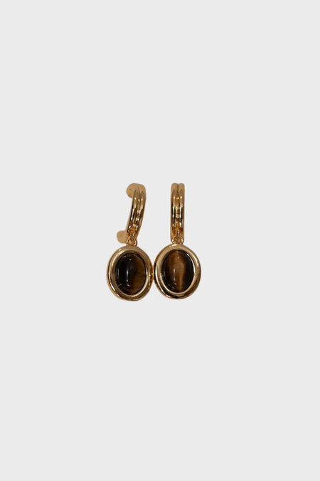 Close-up of Anaïs & Aimee Tiger’s Eye Juniper Drop Earrings with oval-shaped tiger’s eye gemstones set in a polished gold finish, showcasing a timeless and elegant design.