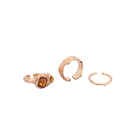 Trio Adjustable Gold Ring Set featuring three unique rings - one with an amber gemstone, a hammered design ring, and a delicate open-ended wavy pattern ring